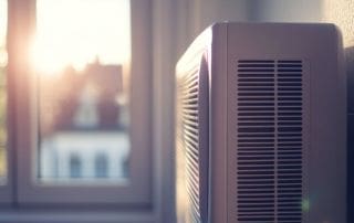 a white residential AC unit sitting beside a window