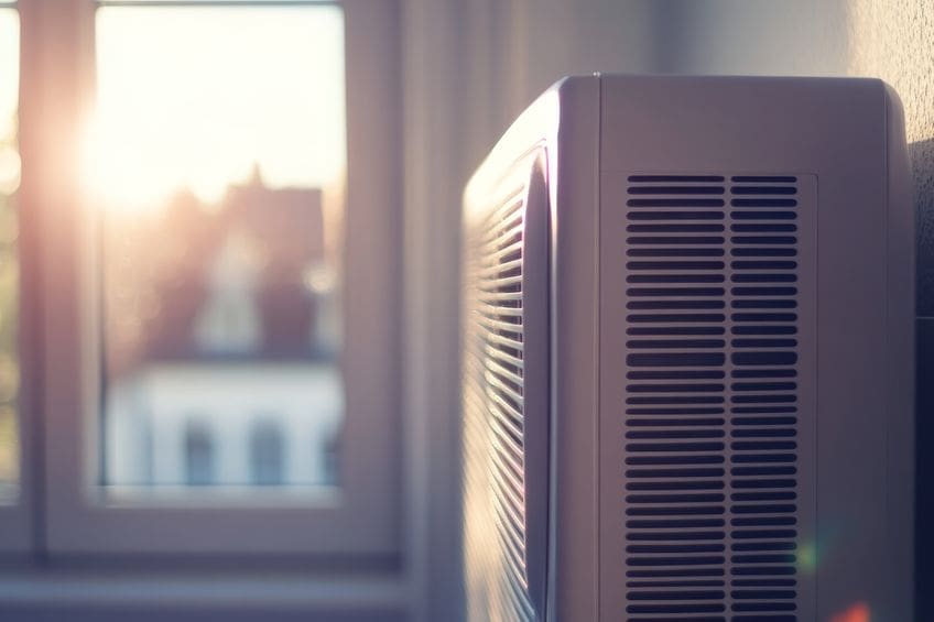 a white residential AC unit sitting beside a window